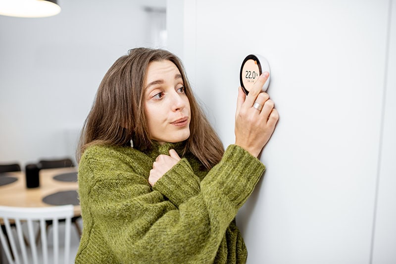 Why Is My Heat Pump Turning On and Off Frequently? A woman turning up the heat.