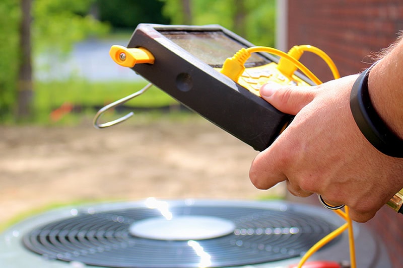 HVAC technician performing maintenance on an outdoor AC system.