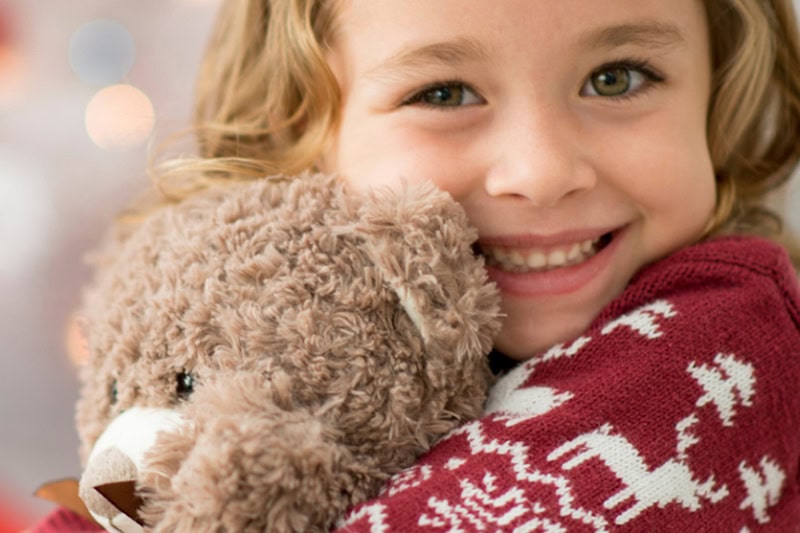 Stay Warm in Your Home With Johnson Heating and Cooling Services. A girl staying warm in her sweater, while holding a teddy bear.